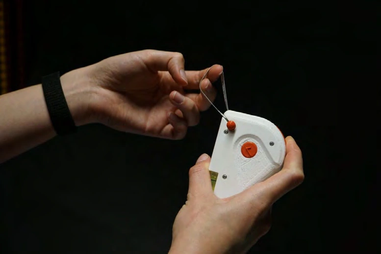 Handheld with confirm and retract buttons and the tape attachment pin in use.
